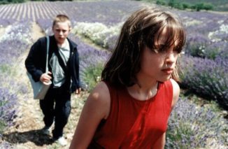 Vincent Rottiers as Joseph and Adèle Haenel as Chloé in The Devils (2002), walking through a lavender field, their silhouettes framed by endless purple blooms under a soft, natural light.