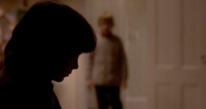 The shadowy silhouette of Elijah Wood in the foreground, with Macaulay Culkin blurred in the background, intensifies the eerie tension of The Good Son (1993)