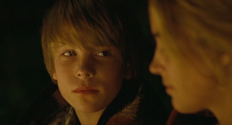 The shallow focus isolates the intense, unspoken fascination of Louis (Steve Le Roi) as he studies the blurred profile of Rosalie (Vahina Giocante). In this quiet, warmly lit moment, his absolute stillness betrays the sudden and heavy arrival of adolescent longing.